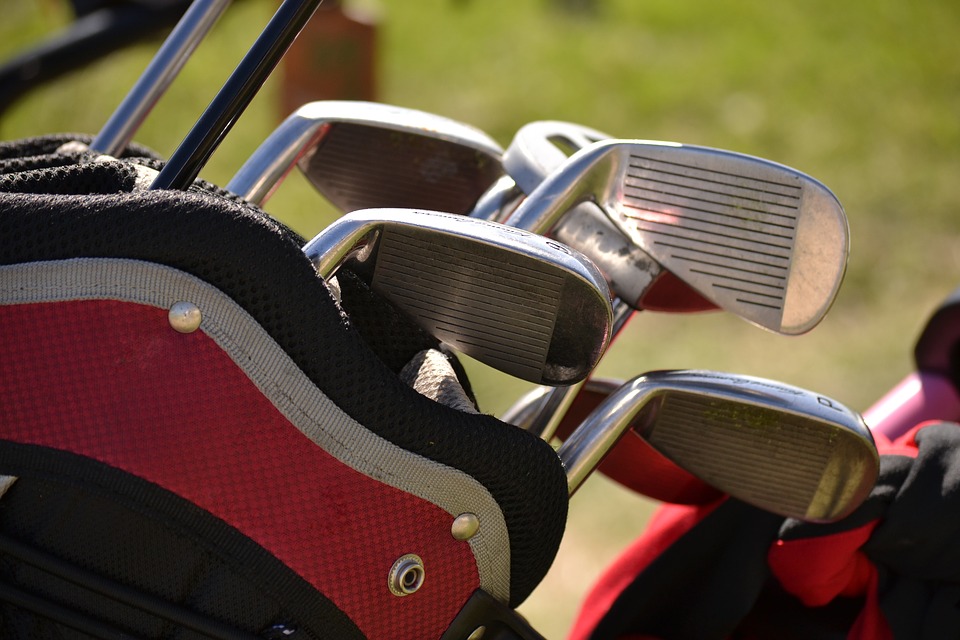 red white and black golf bag with clubs